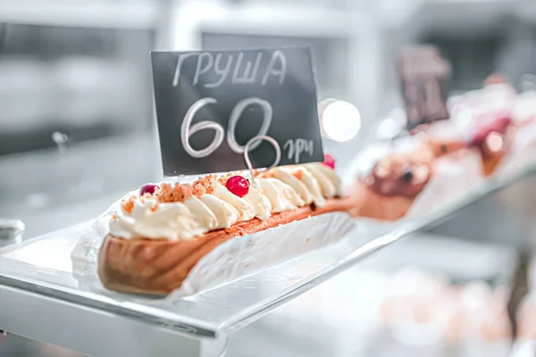 Eclair Śmietaną Ozdobione Orzechami Jagody Jest Wystawie Zbliżenie Biały Jasny — Zdjęcie stockowe