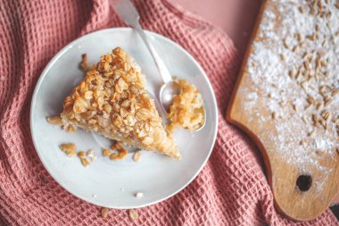 Beyaz tabakta yulaflı turta az önce pişmiş. Pembe havluyla yakın plan, kaşıkla. Kopyalama uzayı. Yatay görünüm.