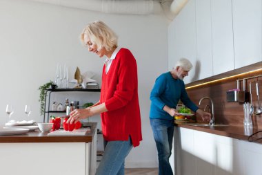 Yaşlı bir çift evde mutfakta yemek hazırlıyor. Büyükbabalar salata için sebze ve sebze kesiyor ve sohbet ediyorlar.