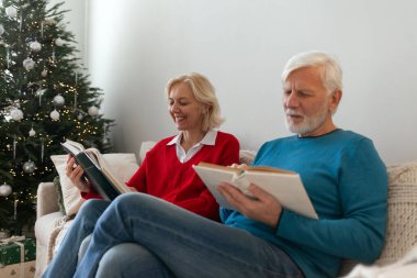 Yaşlı yaşlılar kanepede oturup birlikte kitap okurlar. Emekliler dinlenir.