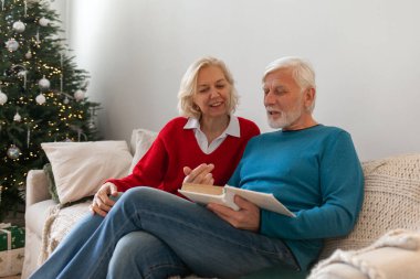 Yaşlı yaşlılar kanepede oturup birlikte kitap okurlar. Emekliler dinlenir.