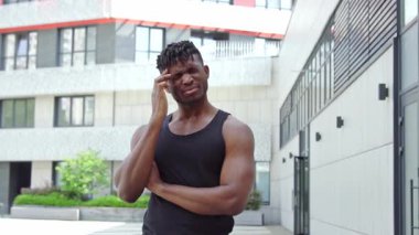 Afrikalı Amerikalı sporcu sokakta baş ağrısı çekiyor, sporcu çocuk migren için şakağına masaj yapıyor ve kendini kötü hissediyor.