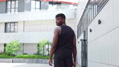 Afro-Amerikalı adam şehir caddesinde yürür ve spor yapmaya davet eder, sporcu adam arar ve şehir arka planında hoş geldin der.
