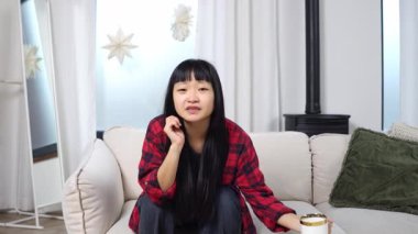 Asyalı genç bir kadın televizyon seyrediyor, umut ve futbol hakkında endişeleniyor, kanepede oturup film seyrediyor ve gergin ve heyecanlı hissediyor.