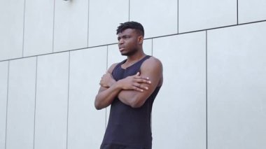 Tişörtlü Afro-Amerikan adam donuyor ve dışarıdaki soğuk, atletik adam yüzünden acı çekiyor.