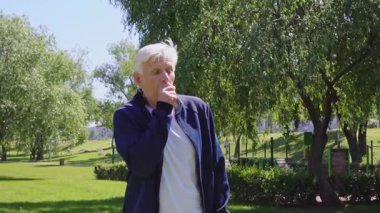 Hasta, yaşlı bir adam öksürüyor ve parkta grip belirtileri gösteriyor. Mutsuz, kır saçlı, dışarıda boğaz ağrısı çeken bir emekli.