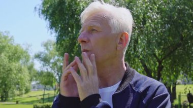 Düşünceli yaşlı adam parkta plan yapar ve düşünür, gri saçlı emekliler dışarıda karar verir ve seçim yaparlar.