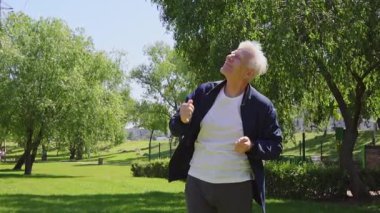 Mutlu yaşlı adam parkta dans ediyor ve kutlama yapıyor, neşeli gri saçlı emekliler seviniyor ve dışarı taşınıyor.