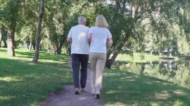 Yaşlı çift parkta koşuyor ve egzersiz yapıyor, gri saçlı emekliler spor yapıyor ve açık havada dinleniyor.