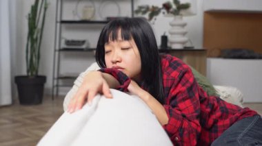 Mutsuz Asyalı kız üzgün ve düşünüyor. Kanepede otururken, düşünceli kadın acı çekiyor ve evde depresyonda rüyalar görüyor.