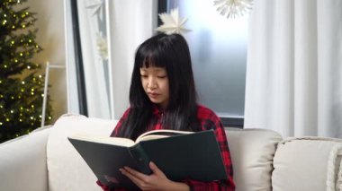 Asyalı kız kanepede oturmuş kitap okuyor, Koreli kadın edebiyat okuyor ve bilgi kazanıyor.