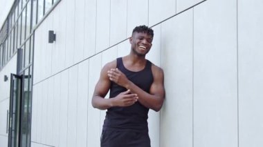 Kulaklıklı Afro-Amerikalı adam kamerayı işaret ederken alay ediyor ve gülüyor. Sportif adam sizi şehir sokaklarında suçluyor ve alay ediyor.