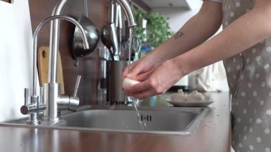 Kadın lavaboda mantar yıkıyor, evde yemek pişiriyor ve mutfakta su altında mantar temizliyor.