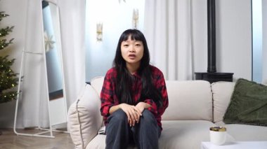 Genç Asyalı kadın televizyon seyrediyor ve evdeki maç için endişeleniyor. Kadın taraftar kazanıyor ve başarısını koltukta kutluyor.