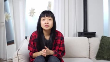 Asyalı genç bir kadın televizyon seyrediyor umut ediyor, üzülüyor ama kaybediyor, üzgün bir kız kanepede oturmuş maçı destekliyor ama başarısız oluyor.