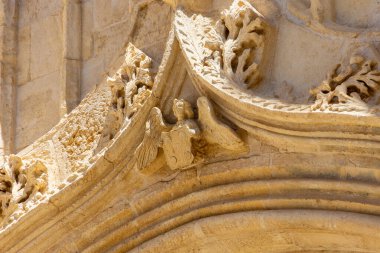 Bir meleğin oymalı tasarımı ile ortaçağ taş kemer yolunun ayrıntıları. Kemer yolu, taş cepheli eski bir binada bulunuyor.