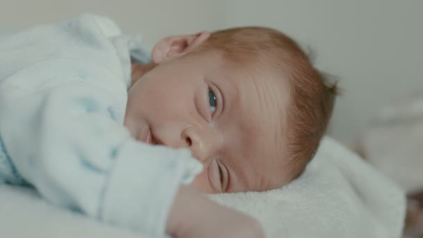 Close-up van het gezicht van een pasgeboren baby in de vroege dagen die wakker wordt en zijn ogen opent. Pasgeboren in de eerste minuten van het leven. Hoge kwaliteit filmisch 4k 12bit beeldmateriaal. — Stockvideo