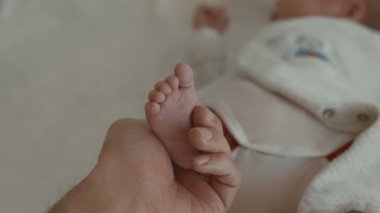 Yeni doğmuş bebek, ilgi ve sevgi, bir çocuğun portresi. Babam bebek ayaklarını elinde tutuyor. Yüksek kalite sinematik 4k 12bit görüntü.