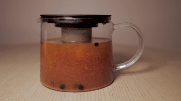 Preparación de té en una jarra - hojas de té flotando en el té. jengibre y limón espino cerval de mar grosella — Vídeos de Stock