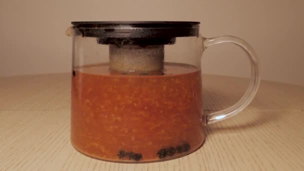 Preparación de té en una jarra - hojas de té flotando en el té. jengibre y limón espino cerval de mar grosella — Vídeo de stock