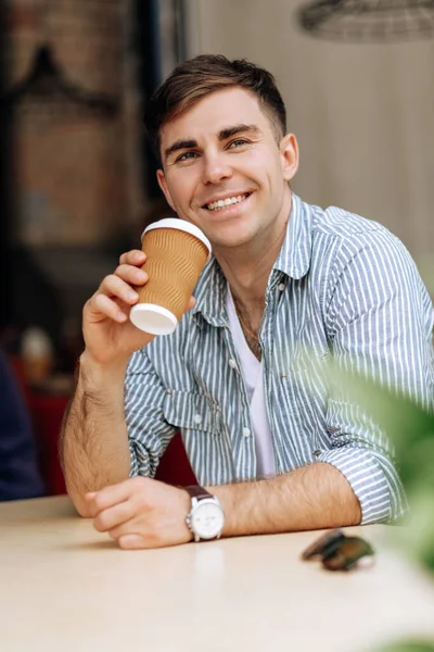 炎热的夏天 一个英俊的黑发男人在咖啡店里喝杯咖啡时微笑着 — 图库照片