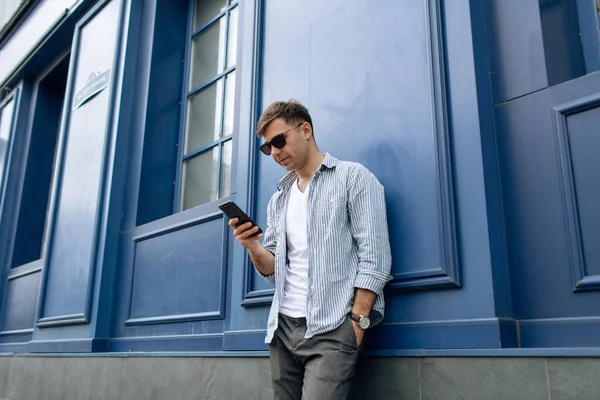 Handsome Brunette Man Sunglasses Smiling While Texting Phone Blue Background — Stock Photo, Image
