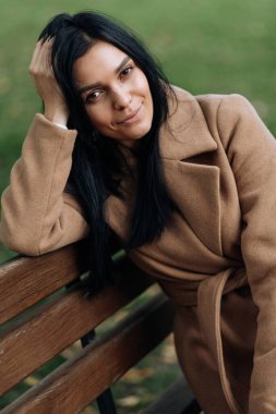 Kahverengi ceketli güzel esmer kameraya bakarken gülümsüyor. Portre