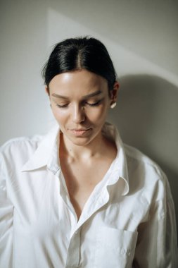 Saçlarını toplamış genç ve güzel bir esmer yere bakıyor. Portre