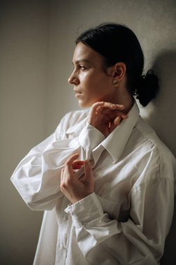 Genç, güzel, esmer bir kadın. Sıradan bir gömlek giyiyor. Başka tarafa bakıyor. Doğal ifade. Ellerinle poz ver.