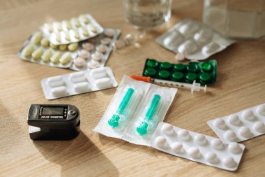 Tıbbi ampuller, şırınga ve haplar masanın üzerinde. Coronavirus virüsü ya da COVID-19 konseptine karşı ilaçlar. Güneş ışınlarının altındaki ilaçlar.