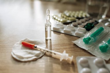 Tıbbi ampuller, şırınga ve haplar masanın üzerinde. Coronavirus virüsü ya da COVID-19 konseptine karşı ilaçlar. Güneş ışınlarının altındaki ilaçlar.