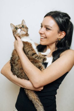 Güzel gülümseyen esmer kız ve kedisi beyaz arka planda