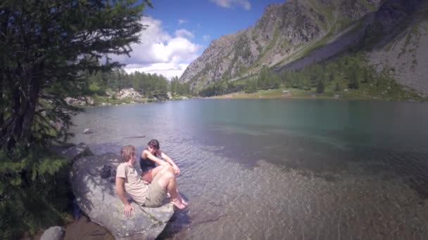 Couple trempant leurs pieds sur le lac — Video