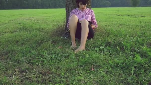 Een vrouw die een boek leest in het park — Stockvideo