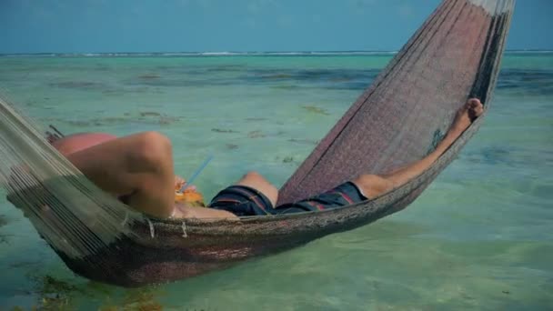 Man relaxes in hammock on the shore — Stock Video