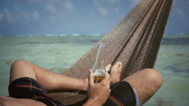 L'homme boit une bière reposant dans l'hamac — Video