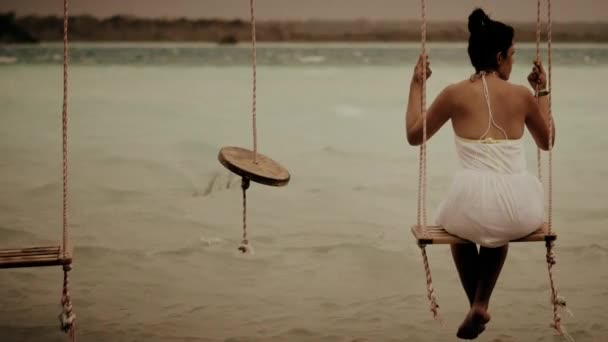 Woman seated on a lagoon swing — Stock Video
