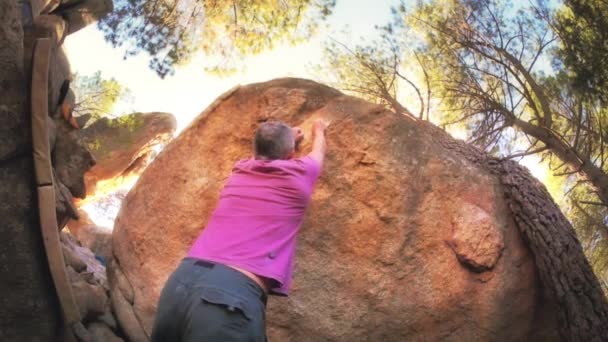 Männchen klettert auf einen riesigen Felsen — Stockvideo
