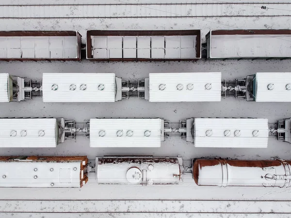 Aerial view of a cargo trains in witer . Freight trains covered with snow on the railway station. Heavy industry. No people.