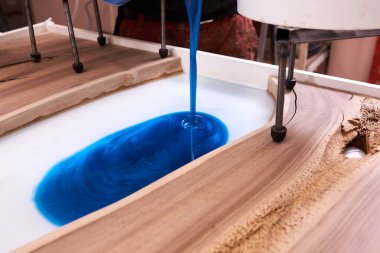 Process making of a craft resin and wood table. Liquid epoxy is poured into a mold with wooden blanks. closeup clipart