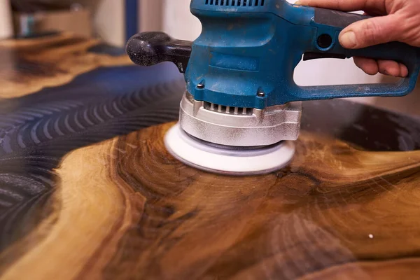 man polishing epoxy table close up.