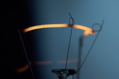 Mavi zemin üzerinde spiral olan elektrik ampulü lambası.