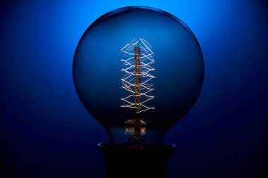 Mavi arkaplanı spiral olan klasik bir Edison ampulü. Retro tarzı lamba.