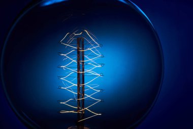 Mavi arkaplanı spiral olan klasik bir Edison ampulü. Retro tarzı lamba.