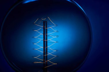 Mavi arkaplanı spiral olan klasik bir Edison ampulü. Retro tarzı lamba.