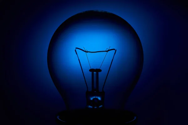 Electric bulb lamp with a spiral on a blue background.