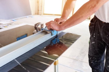 Seramik kesici kullanarak seramik fayanslar kesen inşaat işçisi