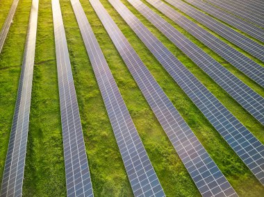 Güneşli bir günde yeşil çayırdaki güneş enerjisi santralinin havadan görünüşü.