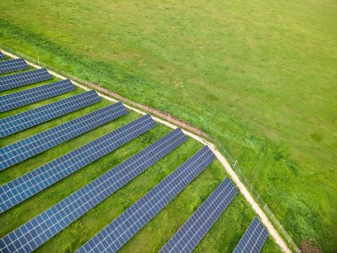 Güneşli bir günde yeşil çayırdaki güneş enerjisi santralinin havadan görünüşü.
