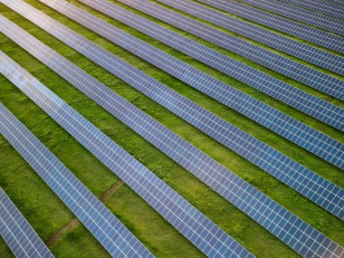 Güneşli bir günde yeşil çayırdaki güneş enerjisi santralinin havadan görünüşü.